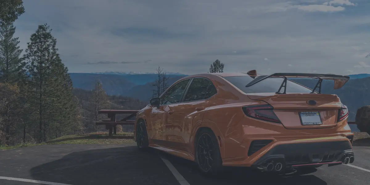 Modified Subaru WRX STI with aftermarket wing on a mountain overlook in the NorCal foothills